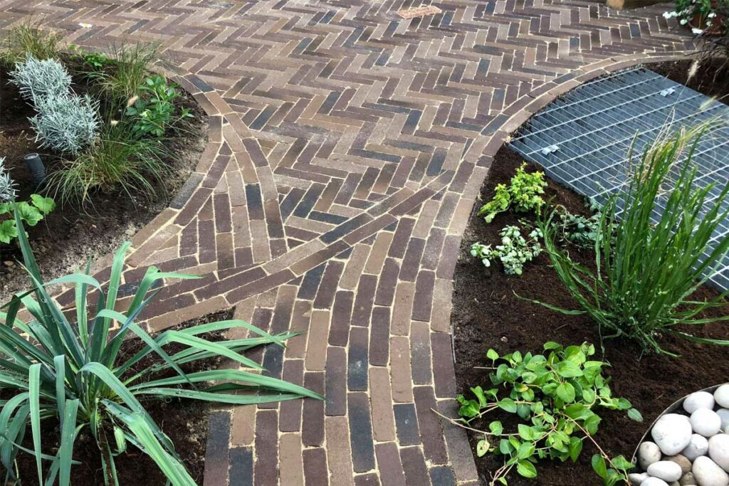 Rotterdam clay pavers are laid in curved patterns around flower beds to create pathways leading through the garden. 